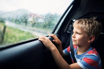 young boy looking out the car window on a rainy day